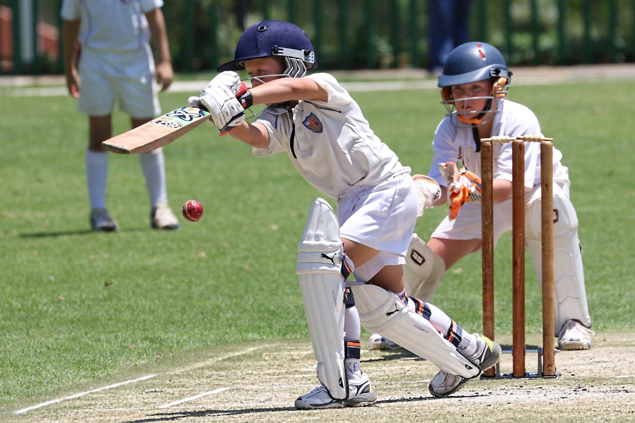 services-03 Young cricketers playing with focus and skill on a sunny outdoor field.